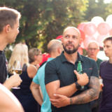 Menschengruppe im Garten mit Ballons im Hintergrund