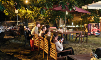 Menschen sitzen zur Feier abends im Garten auf Bänken.