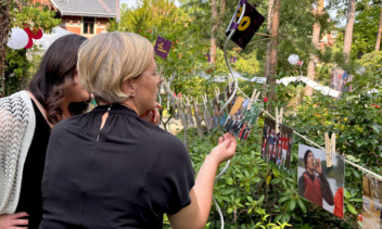 2 Frauen schauen auf Bider, die an einer Leine mit Klammern im Garten befestigt worden.