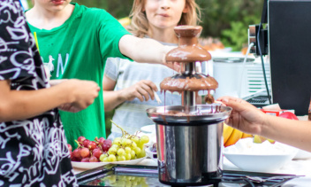 Kinder im Hintergrund. Im Vordergrund steht ein Schokobrunnen