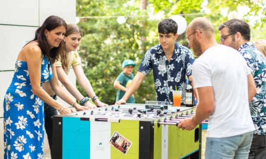 5 Personen spielen Kicker im Garten von Sandstein