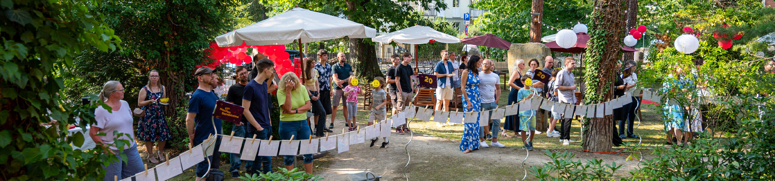 Menschen stehen im festlich geschmückten Garten der Firma SandsteinNM