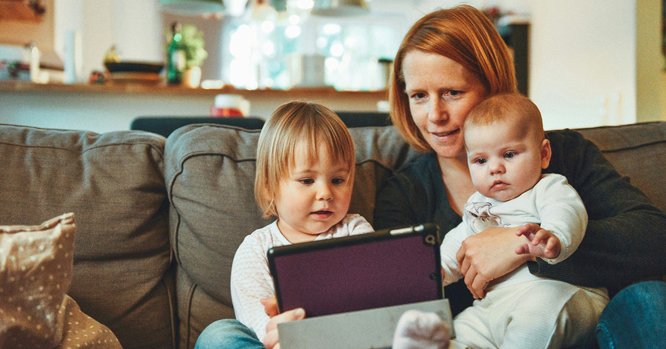 Foto: Mutter mit Kindern auf Sofa und Tablet in der Hand