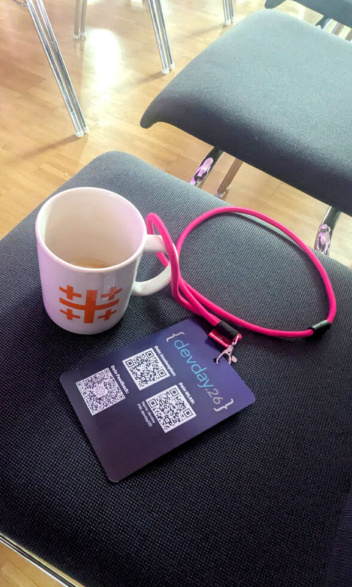 Auf einem Stuhl steht eine Kaffeetasse und eine Einlass-Karte an einem pinken Band.