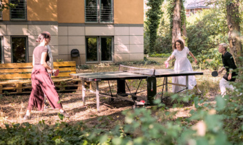 Foto: Personen spielen Tischtennsi im Garten