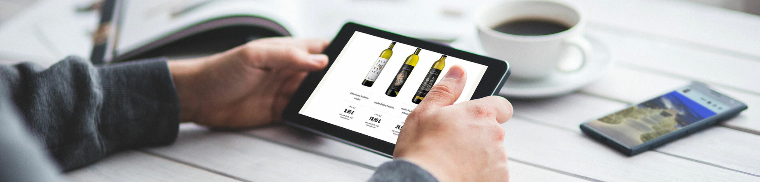 Grafik: Zwei Hände halten Tablet mit Website Schloss Wackerbarth