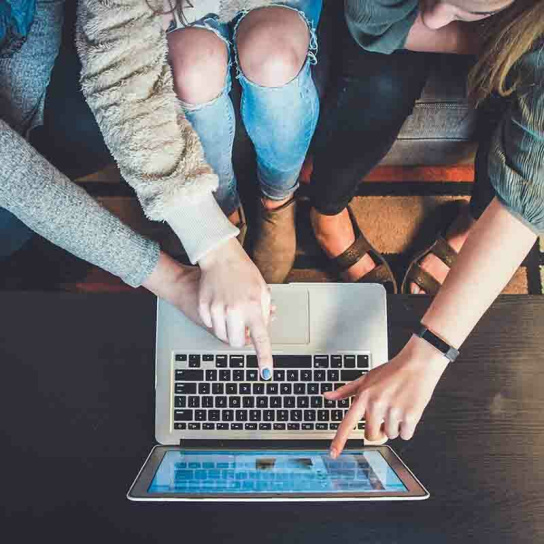 mehrere Hände zeigen auf Laptop