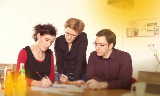 Foto: Drei Personen bei einer Teambesprechung