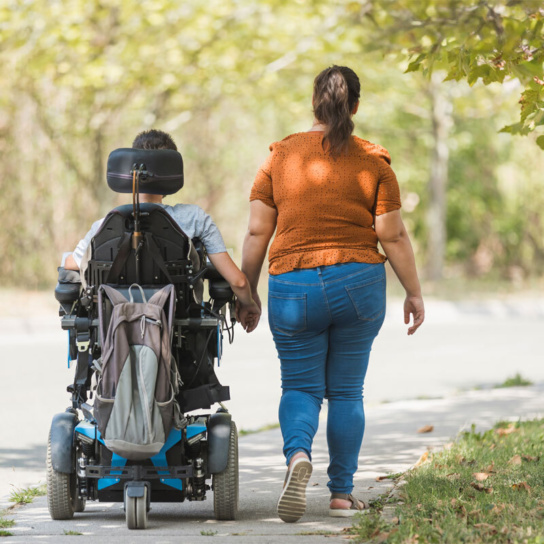 Mann im Rollstuhl und Frau gehen spazieren