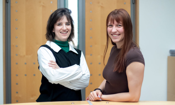 Zwei Frauen blicken in die Kamera und Lächeln.