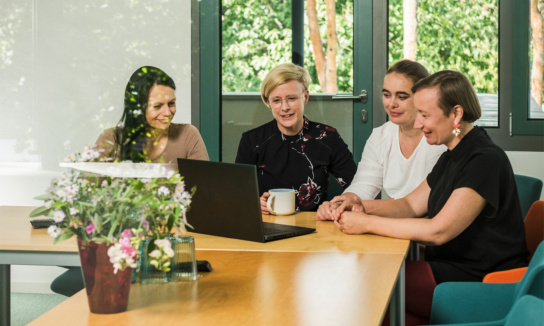 Foto: vier Personen vor Laptop