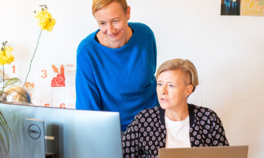 2 Frauen schauen gemeinsam auf einen Monitor und besprechen sich.