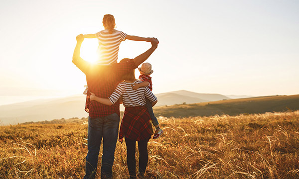 Foto: Eine Familie steht auf einem sonnigen Feld.