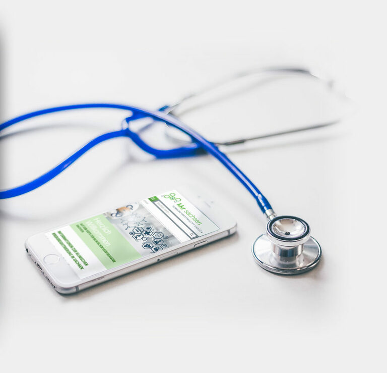 Foto: Smartphone mit Website, daneben ein Stethoskop