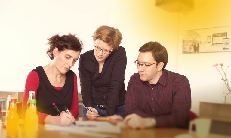 Usability: Heuristische Evaluation Foto: Drei Personen bei einer Teambesprechung.