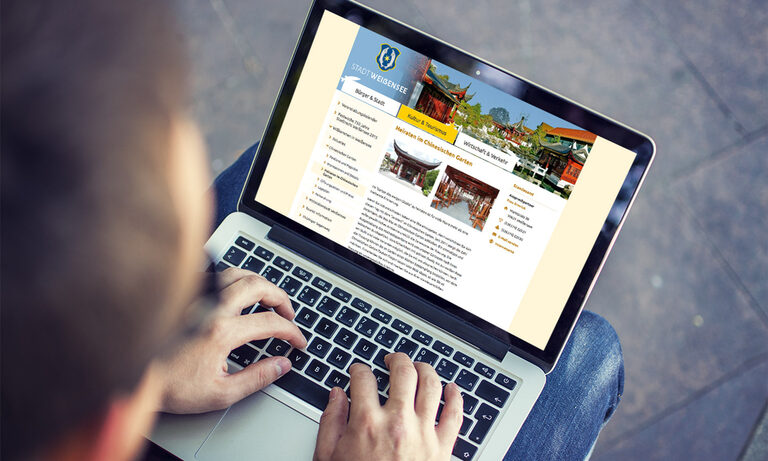 TYPO3 für Stadtportale Foto: Mann an Laptop mit Website der Stadt Weißensee