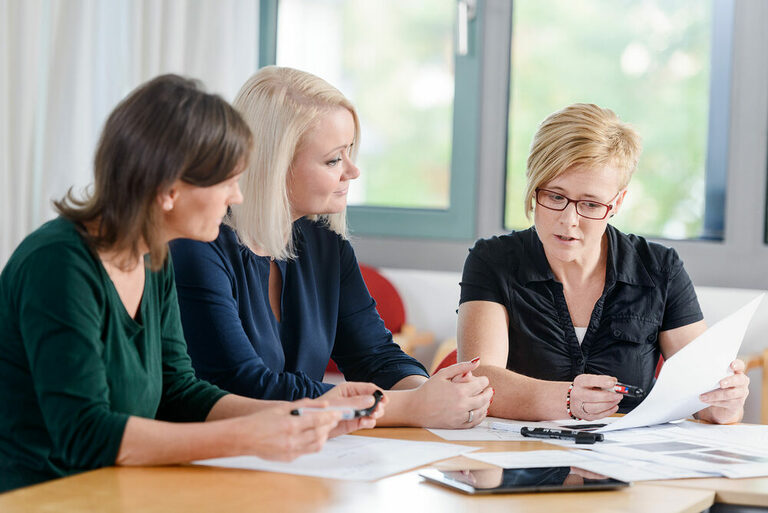 Foto: Drei Frauen in einer Beratung am Tisch.