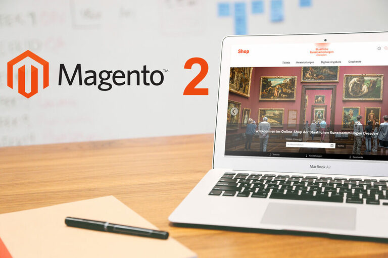 Grafik: Magento 2 Logo neben Laptop mit SKD Seite