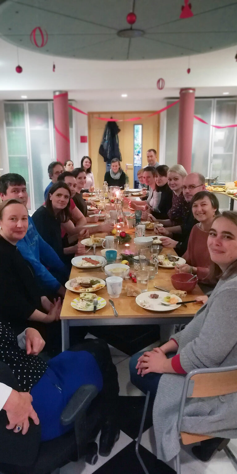 Foto: Gruppe Menschen an einem langen Tisch mit Essen