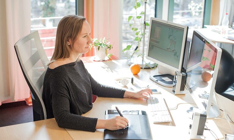 Foto: Frau an einem Schreibtisch mit Desktops